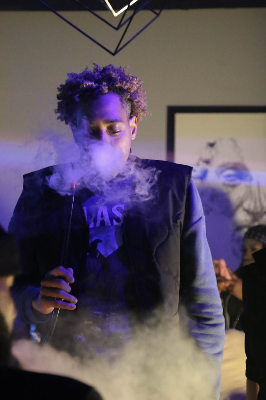 A guest surrounded by purple-lit smoke on the District385 floor