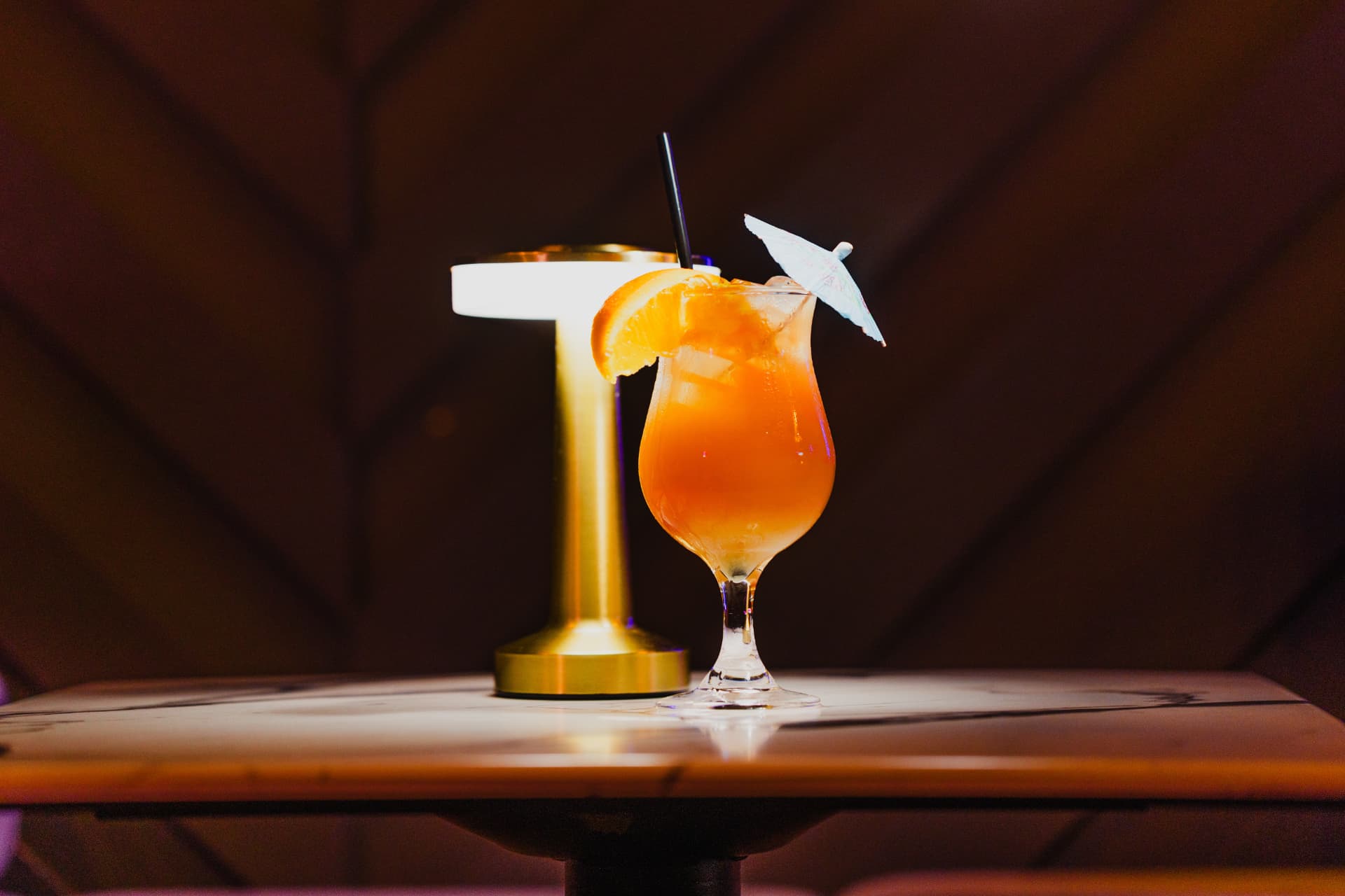 Tropical cocktail with orange slice and paper umbrella at District385