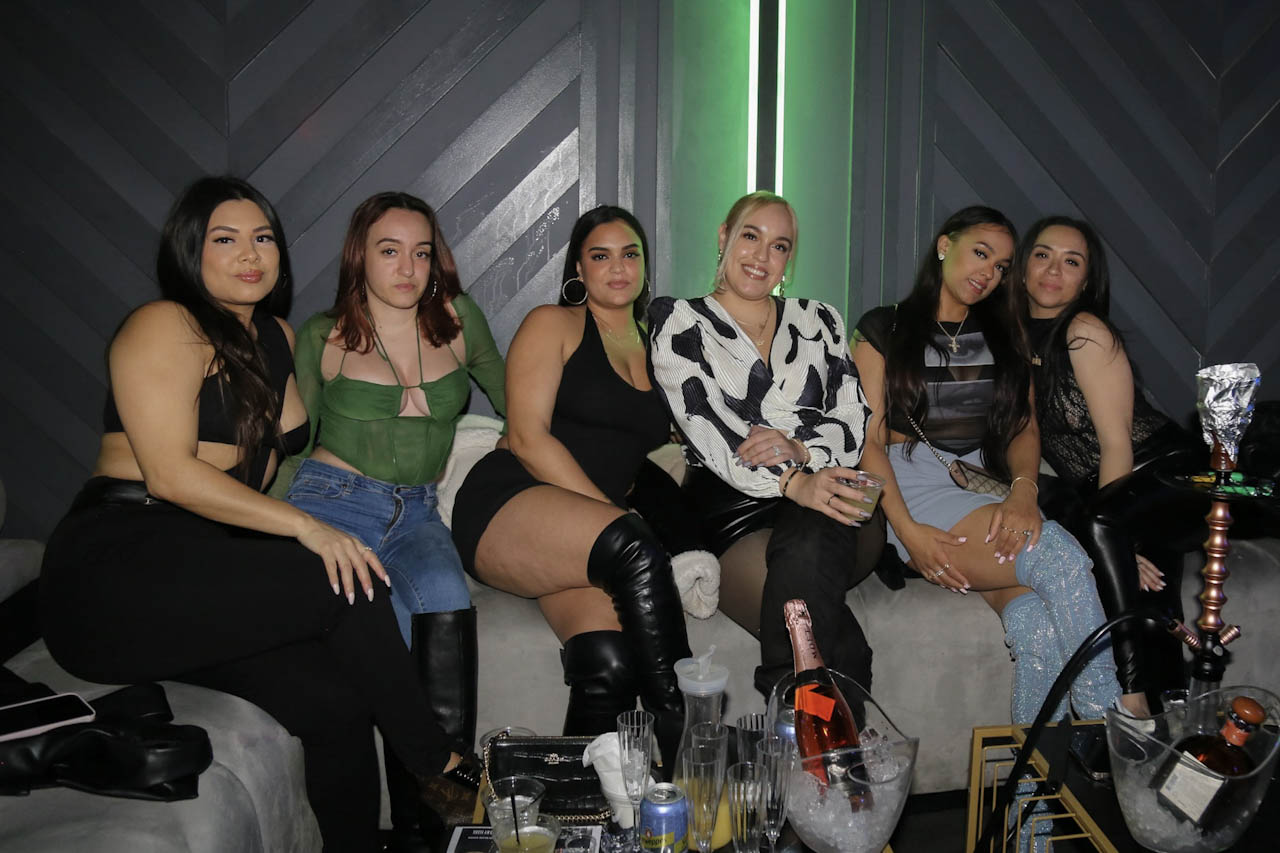 A large group seated at a booth with hookah and bottles at District385