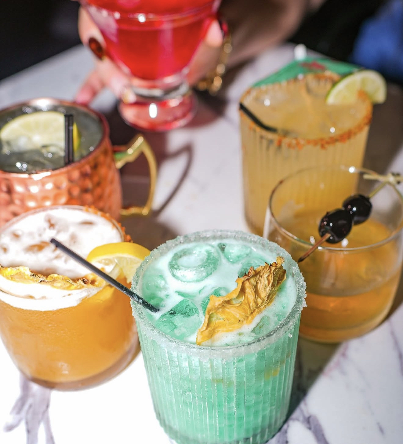 A spread of colorful house cocktails on a marble table at District385