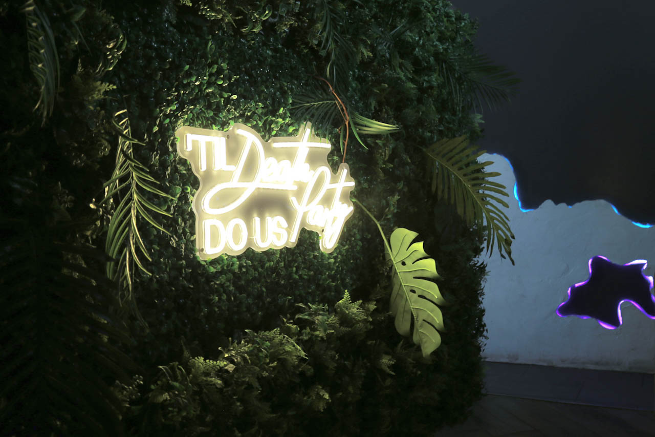 Neon script sign set into the greenery wall at District385