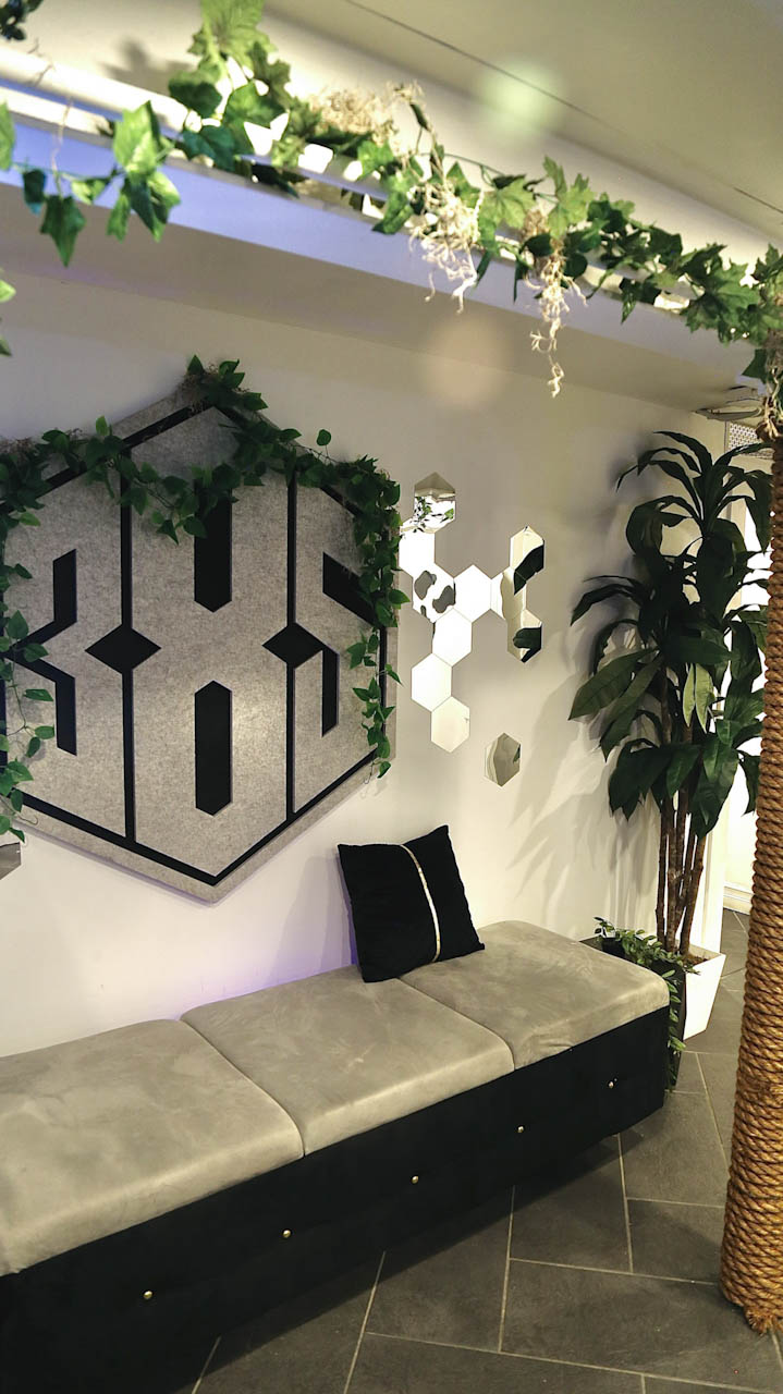 The 385 logo wall above a banquette framed with greenery