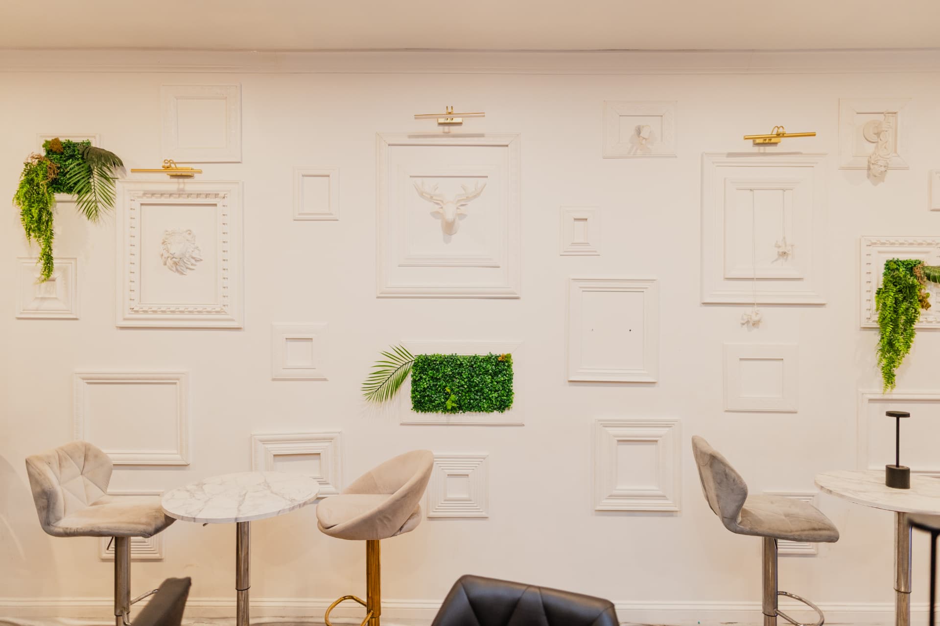 White sculpted frame wall with greenery above marble high-tops at District385