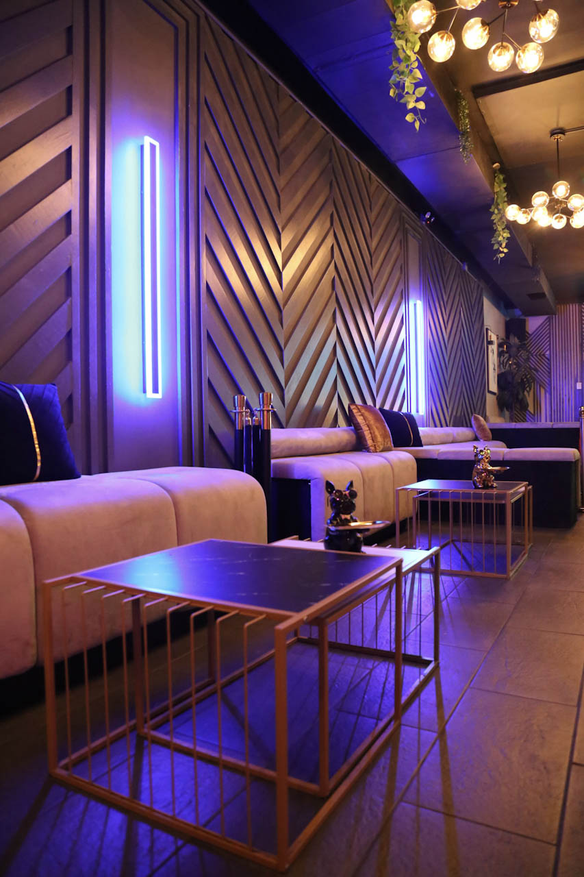 Purple neon lighting over the lounge booths and gold tables at District385