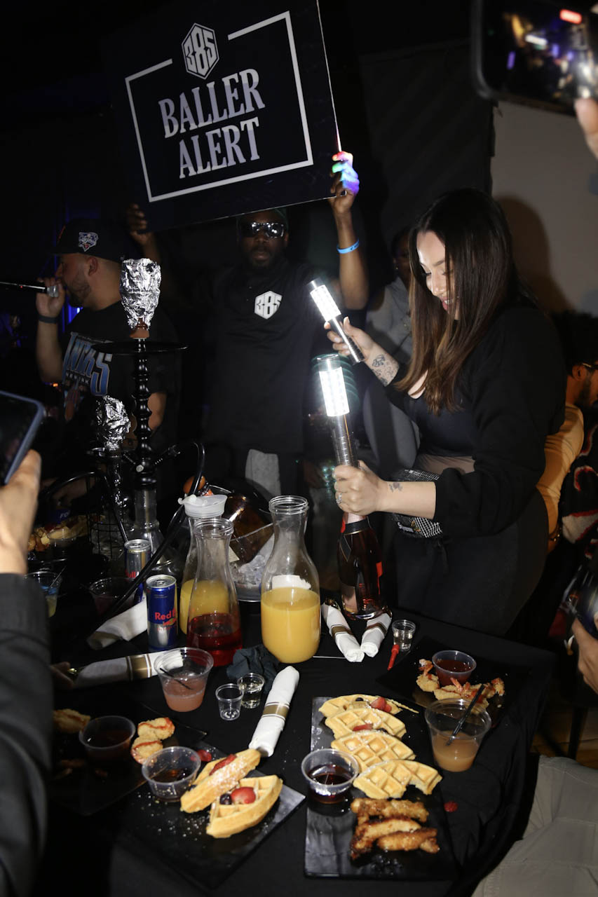 A VIP table set with bottles, mixers and a food spread at District385